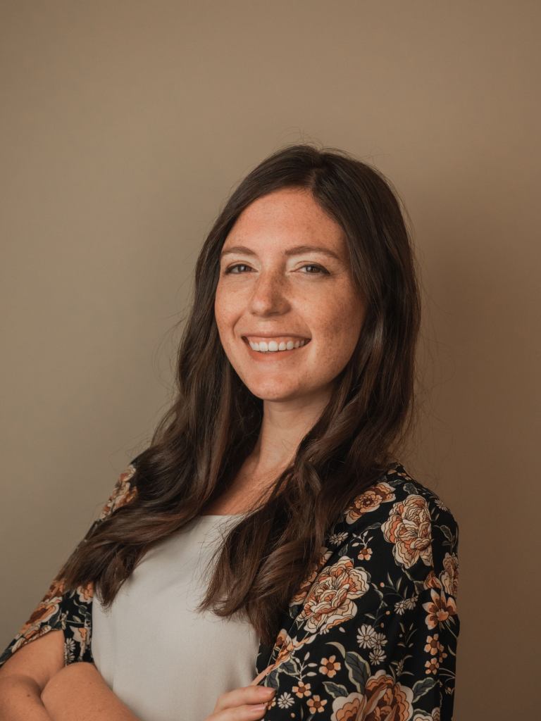 A portrait photo of a young white woman with long brown hair smiling at the camera.
